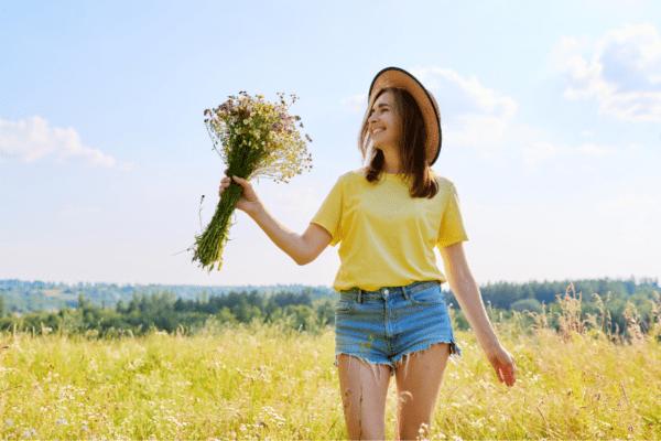 A lady in her 30s in a field holding flowers